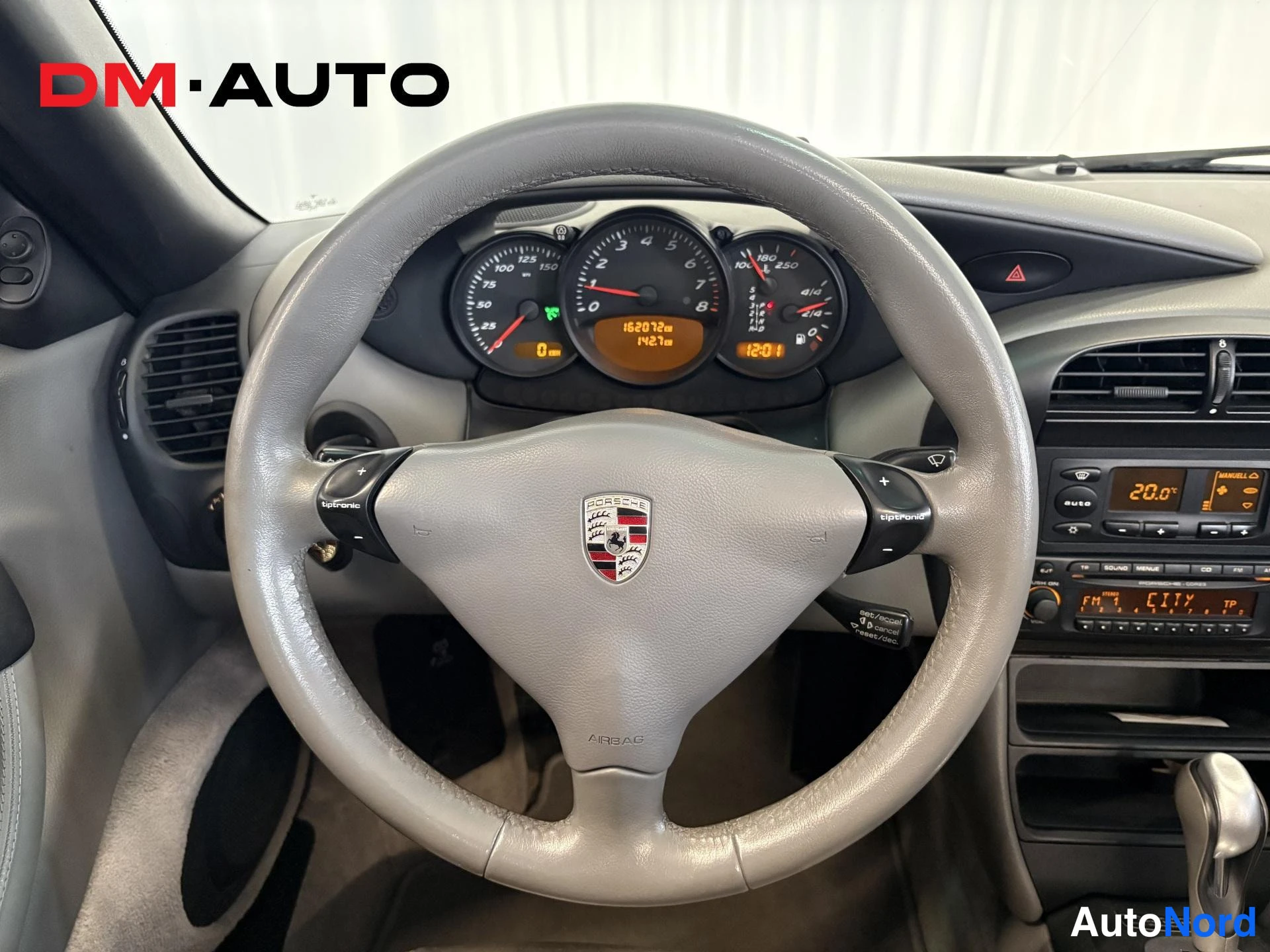 Muu: Ohjauspyörän ja mittariston lähikuva: Porsche-tunnuksellinen ohjauspyörä, mittarit ja Tiptronic-kytkimet, matkamittari 162072 km.