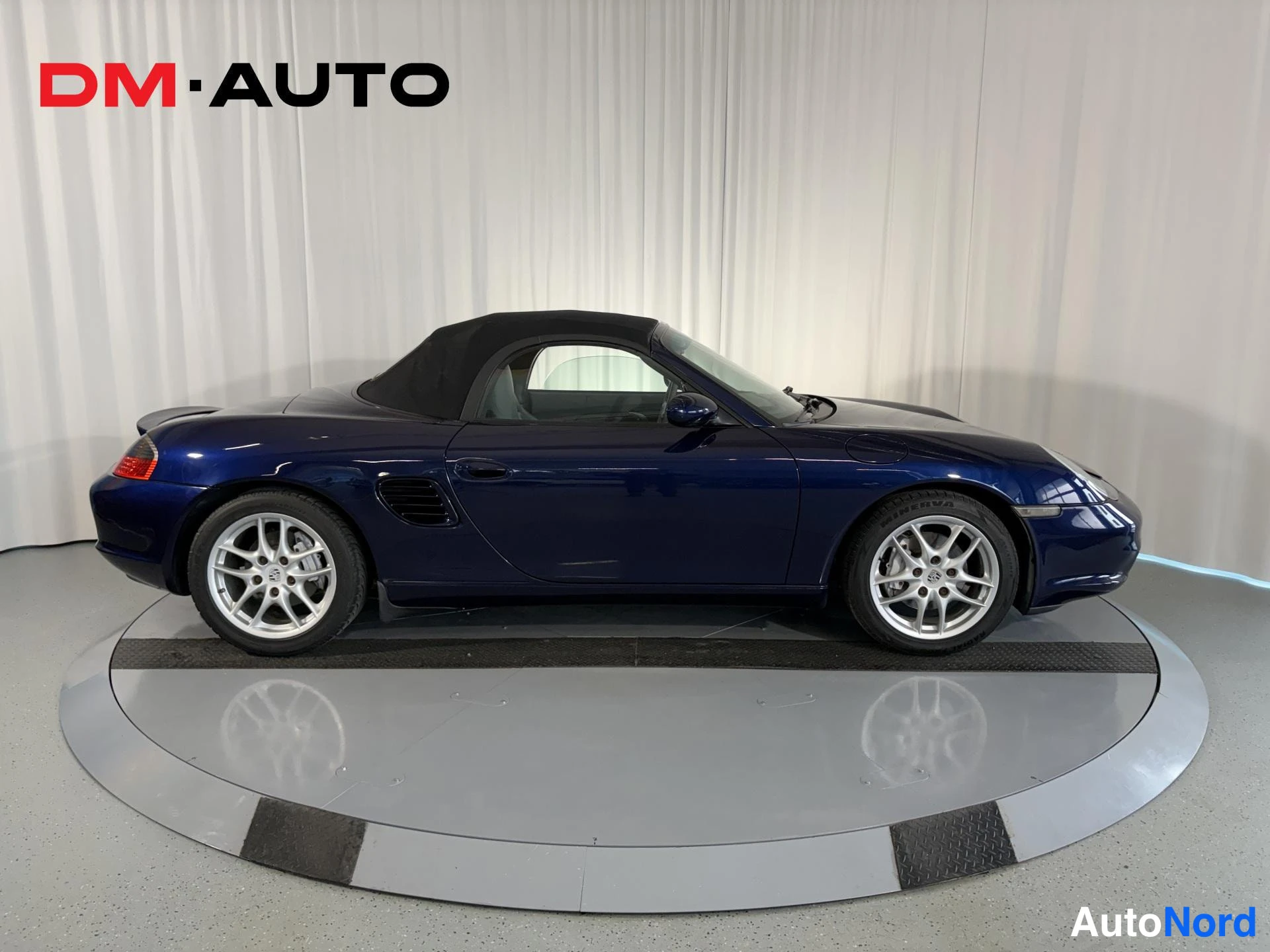 Takaviisto: Porsche Boxster 2.7 2003, sivunäkymä tummansinisestä avomallista, katto ylhäällä