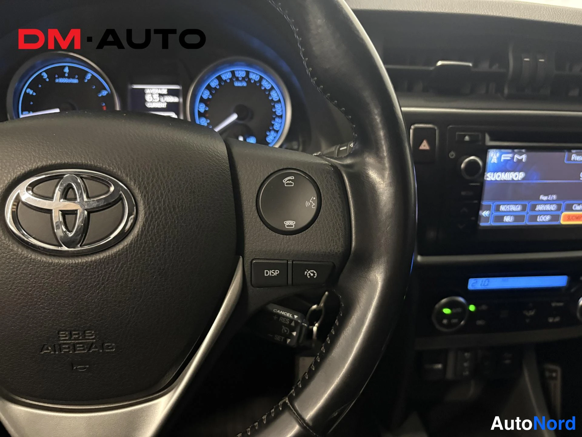 Muu: Ohjauspyörä ja kojelauta: Toyota-merkki,(DISPLAY)- ja puhelinpainikkeet, mittariston valot ja radio näkyvissä.