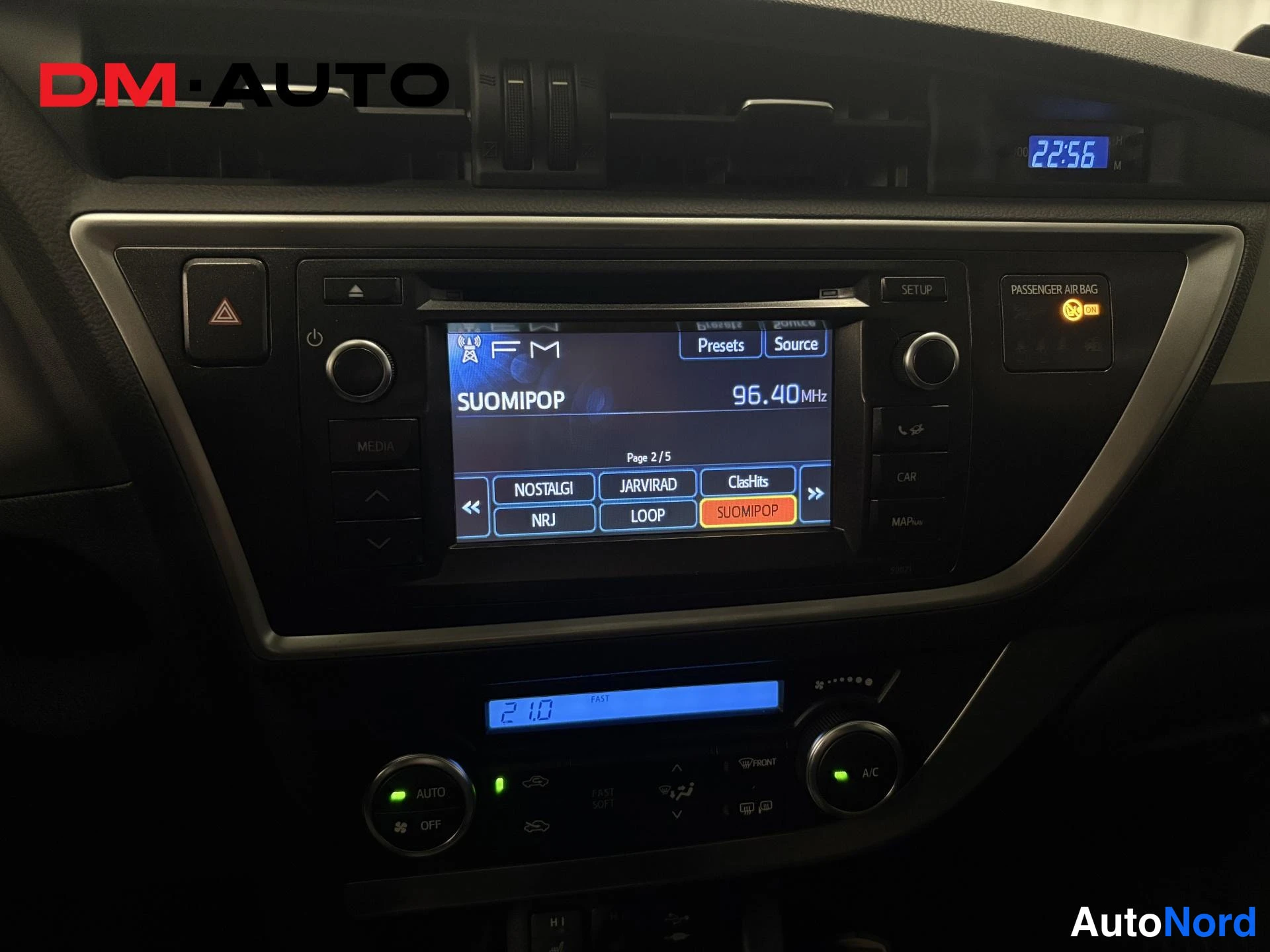 Muu: Keskikonsoli: radio näyttää FM-aseman SUOMIPOP 96.40 MHz, ilmastointipaneelissa AUTO- ja A/C-painikkeet, kello näyttää 22:56.