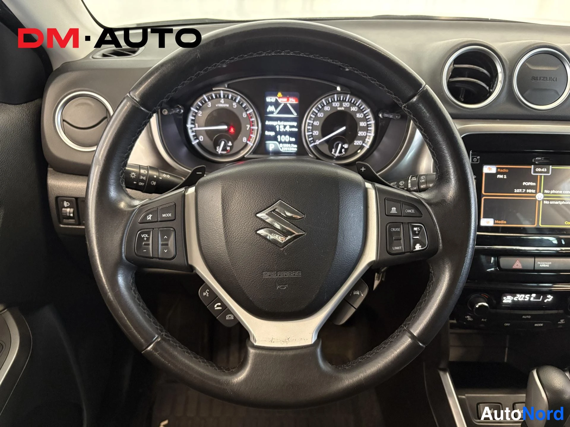 Edestä: Suzuki Vitara: ohjauspyörän lähikuva ja mittaristo, lukemissa noin 184,100 km, keskikonsolin radio näytöllä.