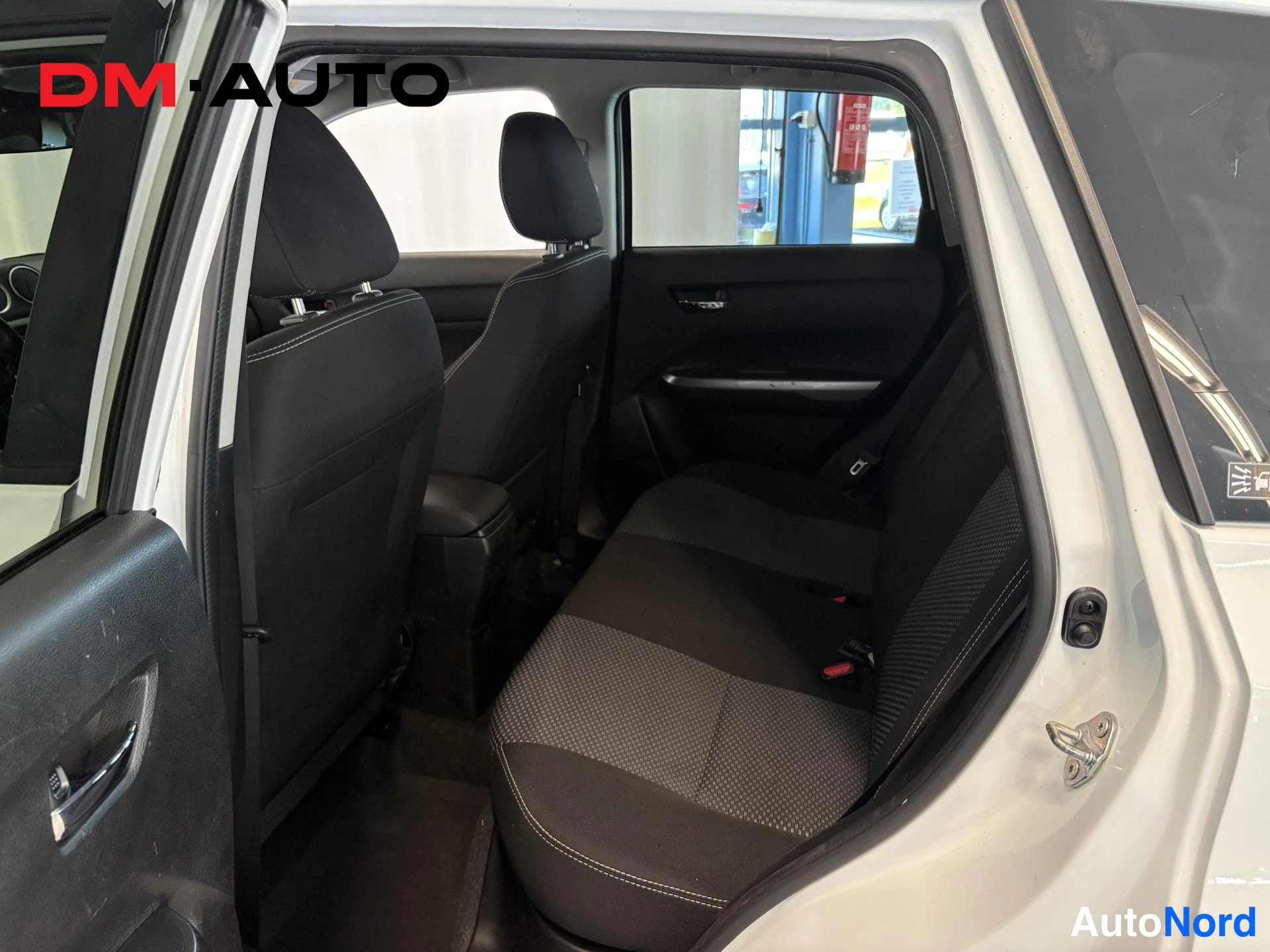 Yksityiskohta: Suzuki Vitara -takaohjaamo vasemmalta katsottuna: takapenkki ja tummat kangasistuimet näkyvät takaovesta.