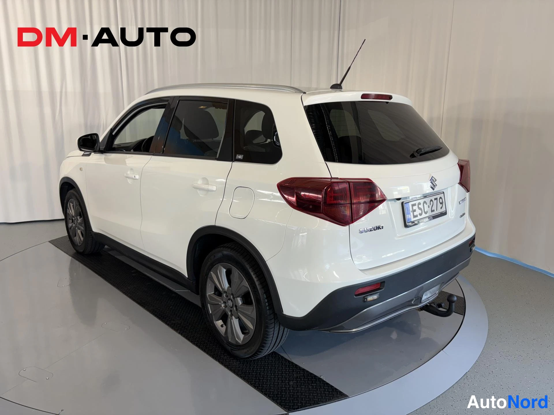 Takaviisto: Valkoinen tila-auto takaapäin ja sivulta, takavalot, rekisterikilpi ja vetokoulu näkyvät.