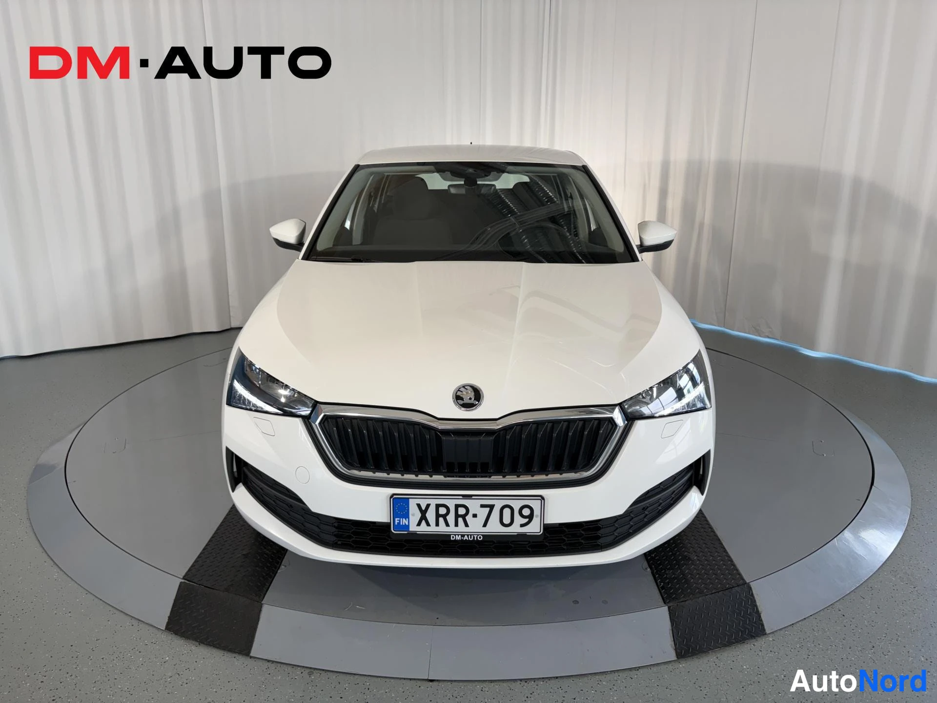 Edestä: Valkoisen Skoda Scan etunäkymä, grilli, ajovalot ja rekisteri.