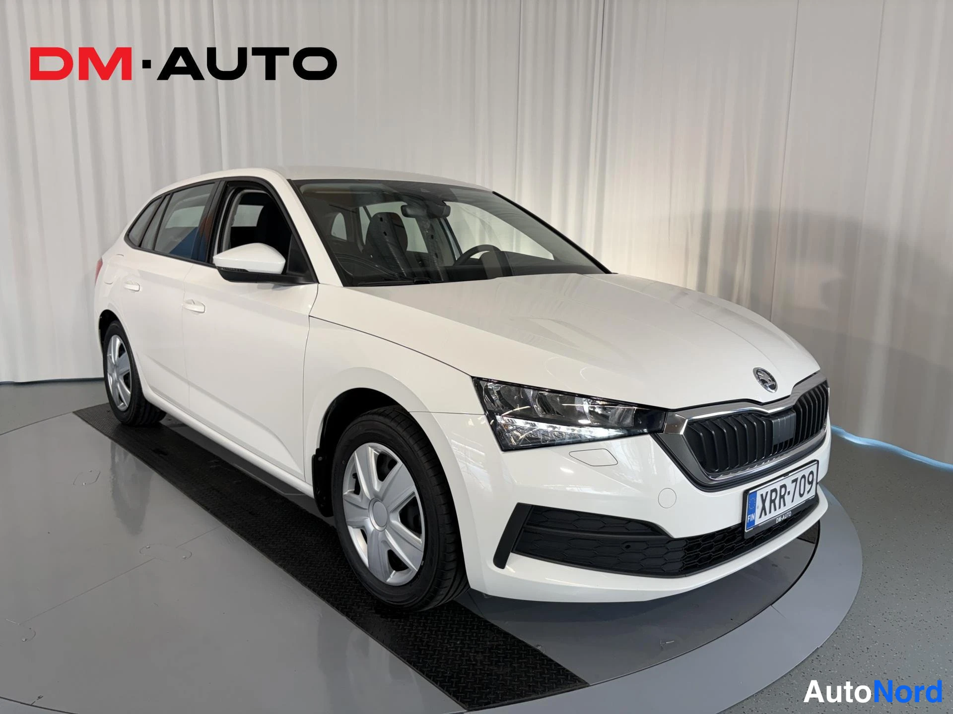 Etuviisto, nokka oikealle: Valkoinen Skoda Scala etuviistosta oikealta, kylki ja keulapuoli näkyvät, rekisteri.