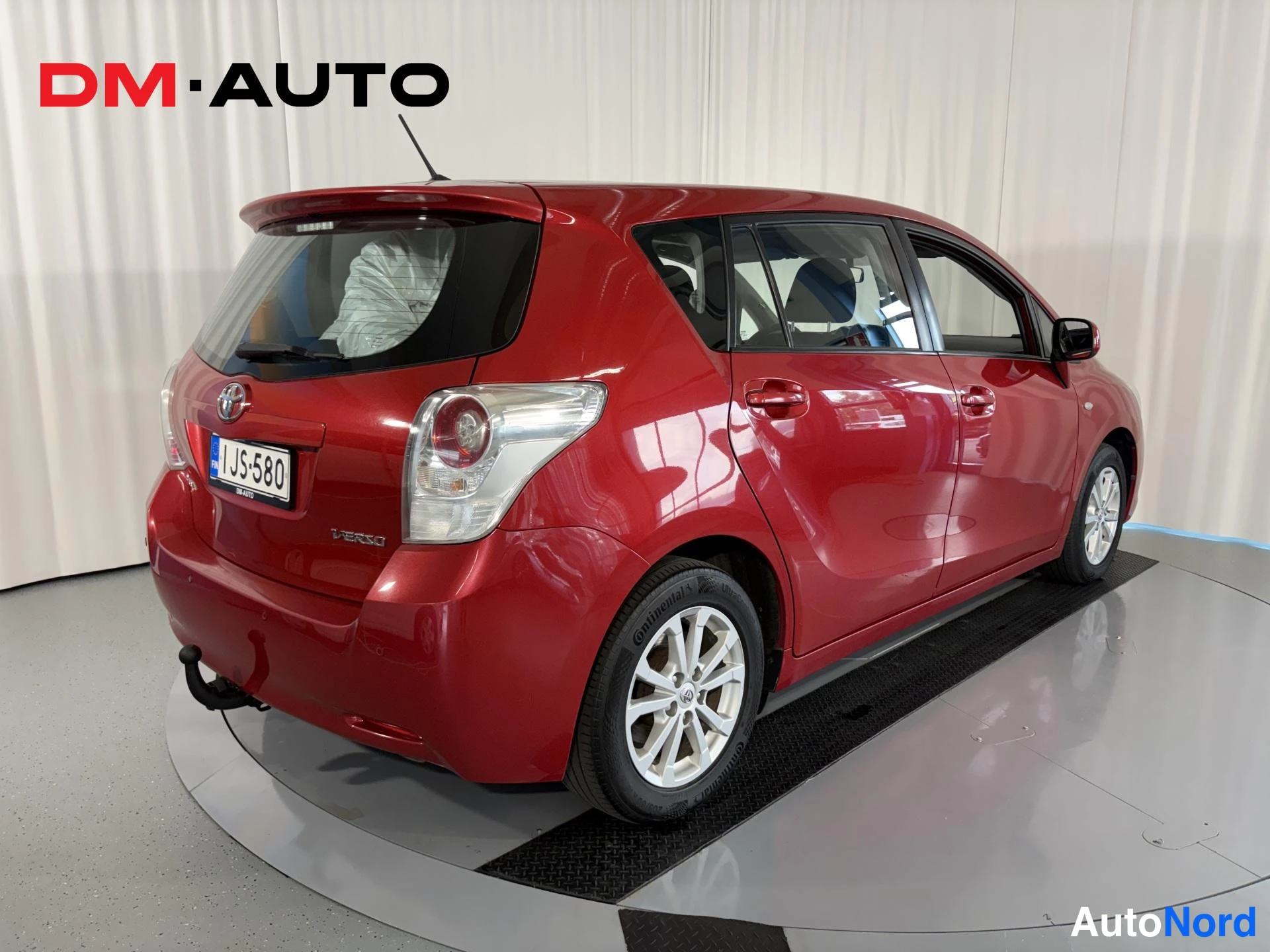 Takaviisto: Punaisen Toyota Verson takakulmanäyttö: takavalot, Toyota-merkki ja -kilpi, vasen kylki ja pelaussarjakin näkyvät.