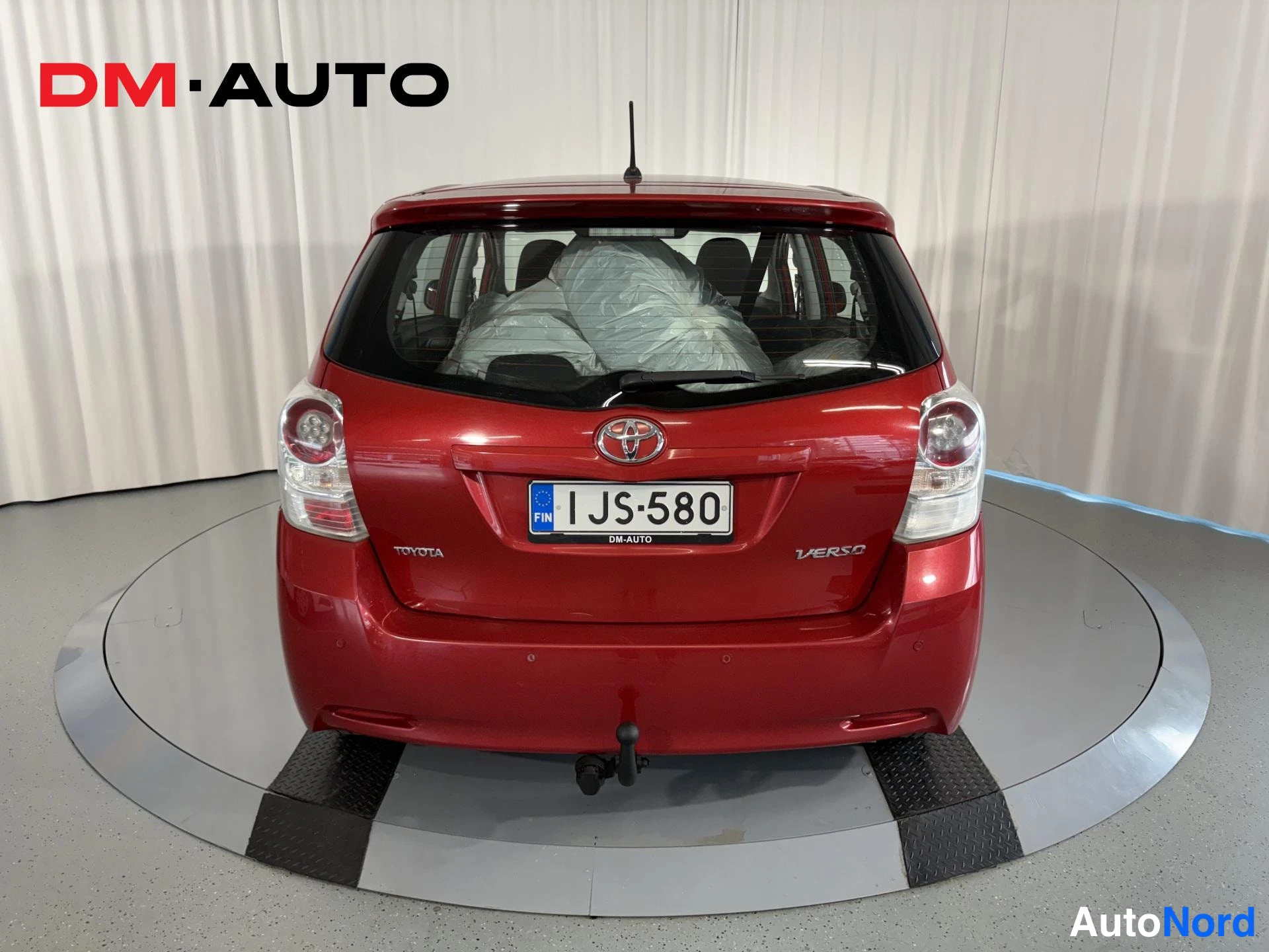 Takaa: Punaisen Toyota Verson takaosan suora näyttö, rekisterikilpi ja vetojinä erottuvat.