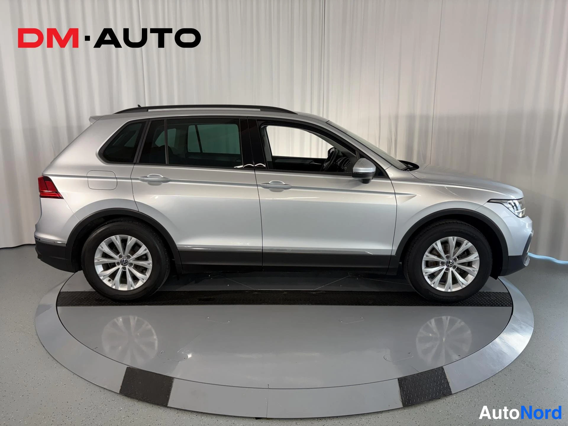 Sivulta: Hopeanvärinen Volkswagen Tiguan sivusta kuvattuna sisätiloissa alustalla.