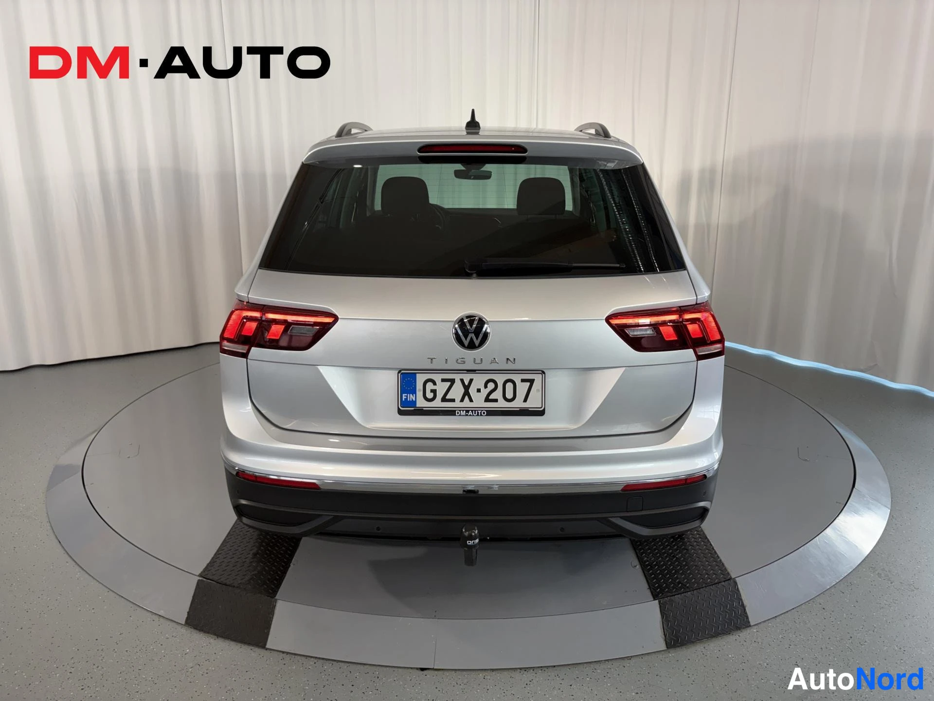Takaa: Hopeanvärinen Volkswagen Tiguan suoraan takaa; TIGUAN-teksti ja rekisteritunnus, vetokoukku näkyvissä.