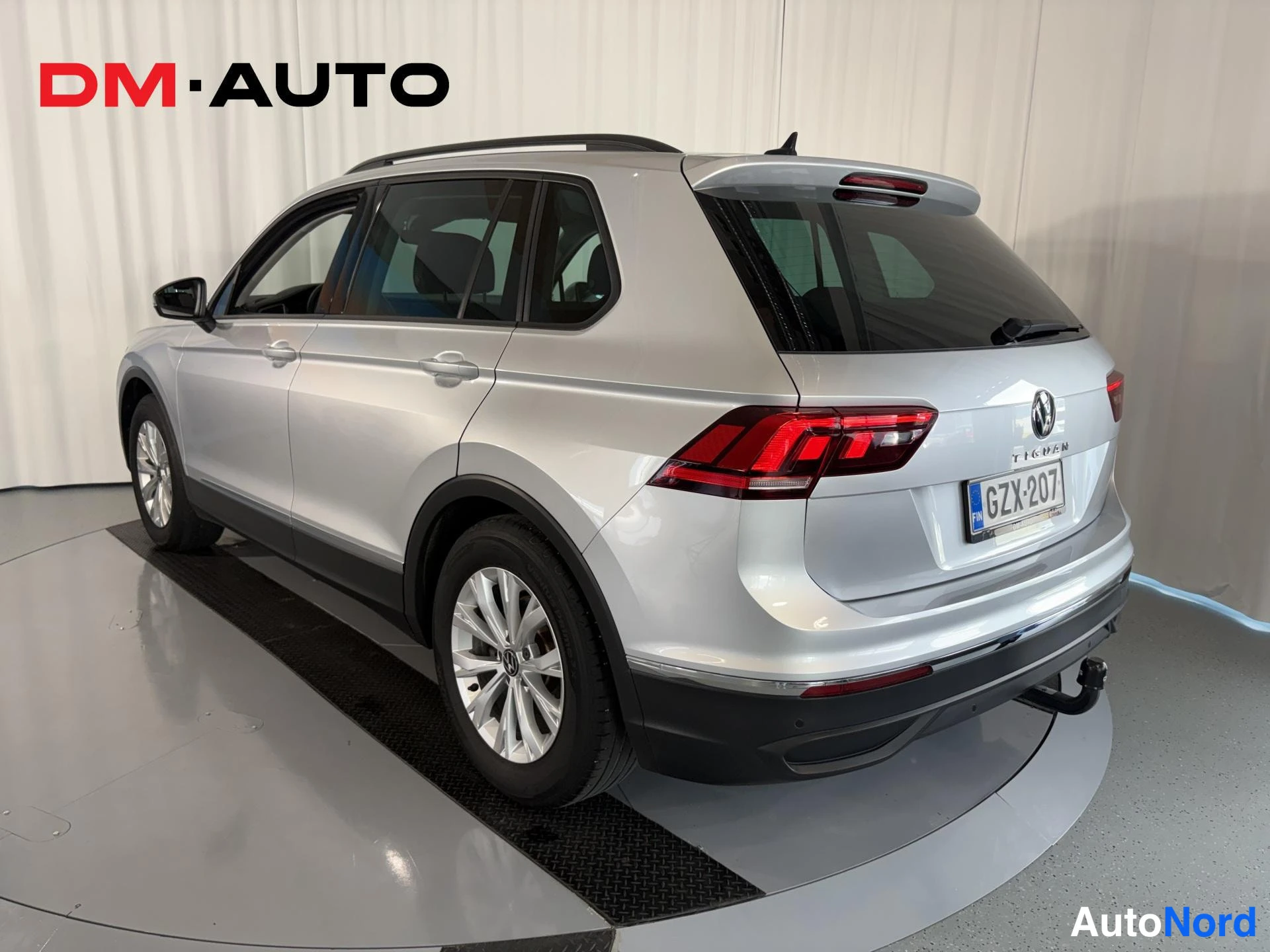 Takaviisto: Hopeanvärinen Volkswagen Tiguan takaa oikealta kuvattuna; rekisteritunnus, kattokaiteet ja vetokoukku näkyvät.