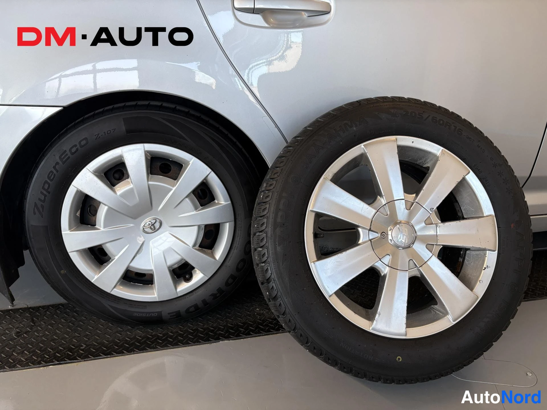 Yksityiskohta: Lähikuva auton takapyörästä Toyota-pyyhkäisyllä ja irronnesta alumiinivanteella varustetusta renkaasta (205/60 R16).