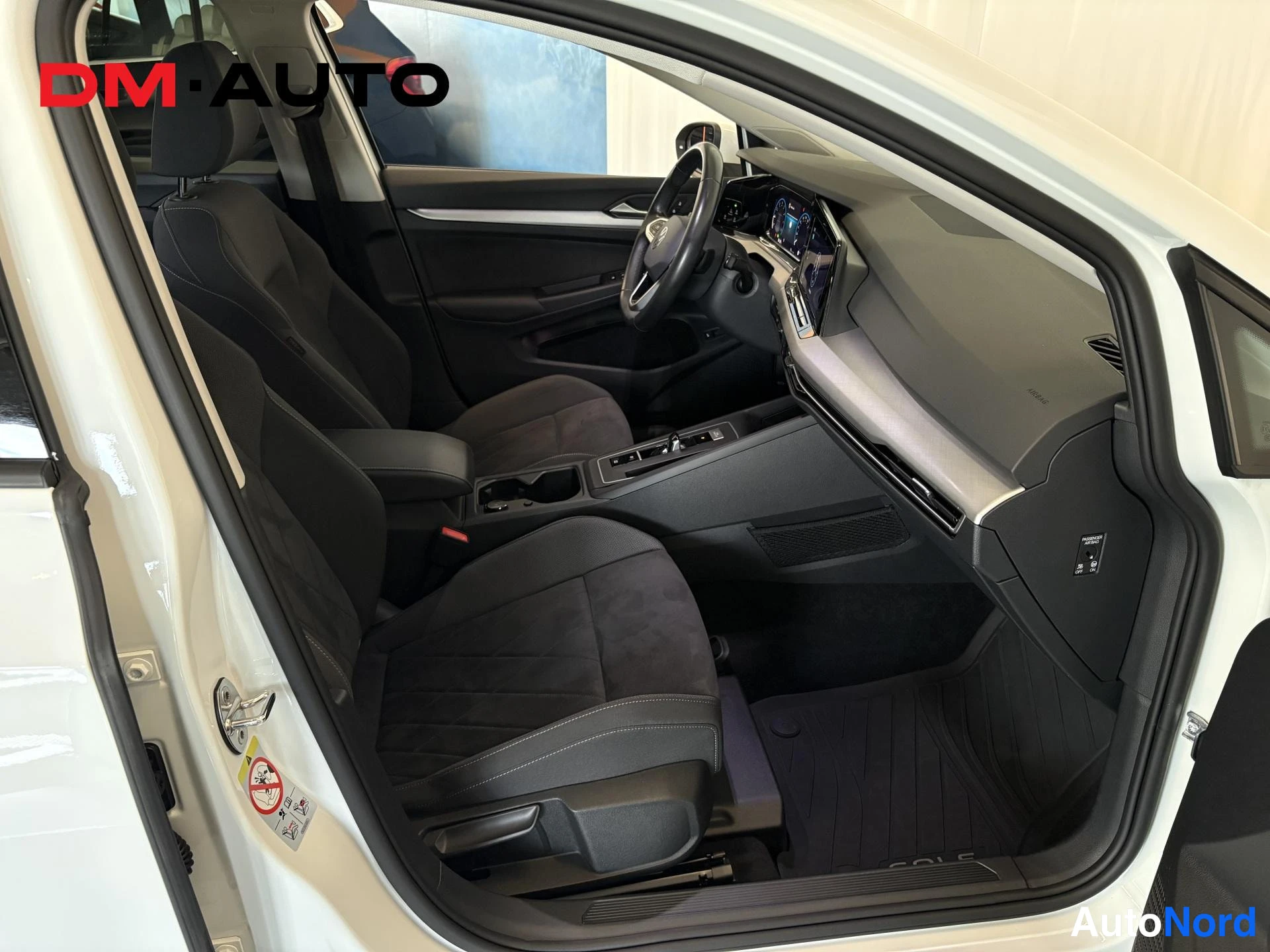 Muu: Volkswagen Golfin etumatkustamo avoimesta kuljettajan ovesta kuvattuna: tummat kangasistuimet, ohjaustehostin, keskikonsolin kosketusnäyttö ja automaattivaihtee