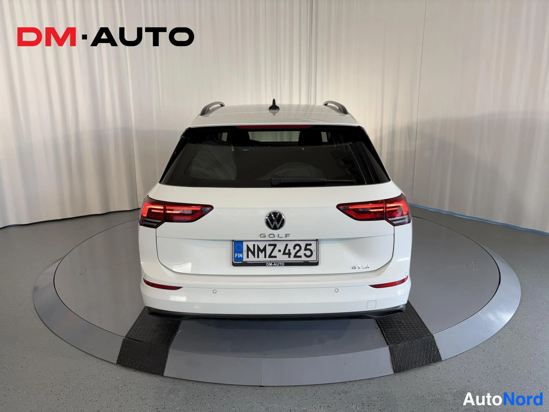 Takaa: Valkoisen farmariauton takaosa suoraan takaa: Volkswagen-merkki, GOLF-teksti, -rekisterikilpi ja punaiset takavalot.