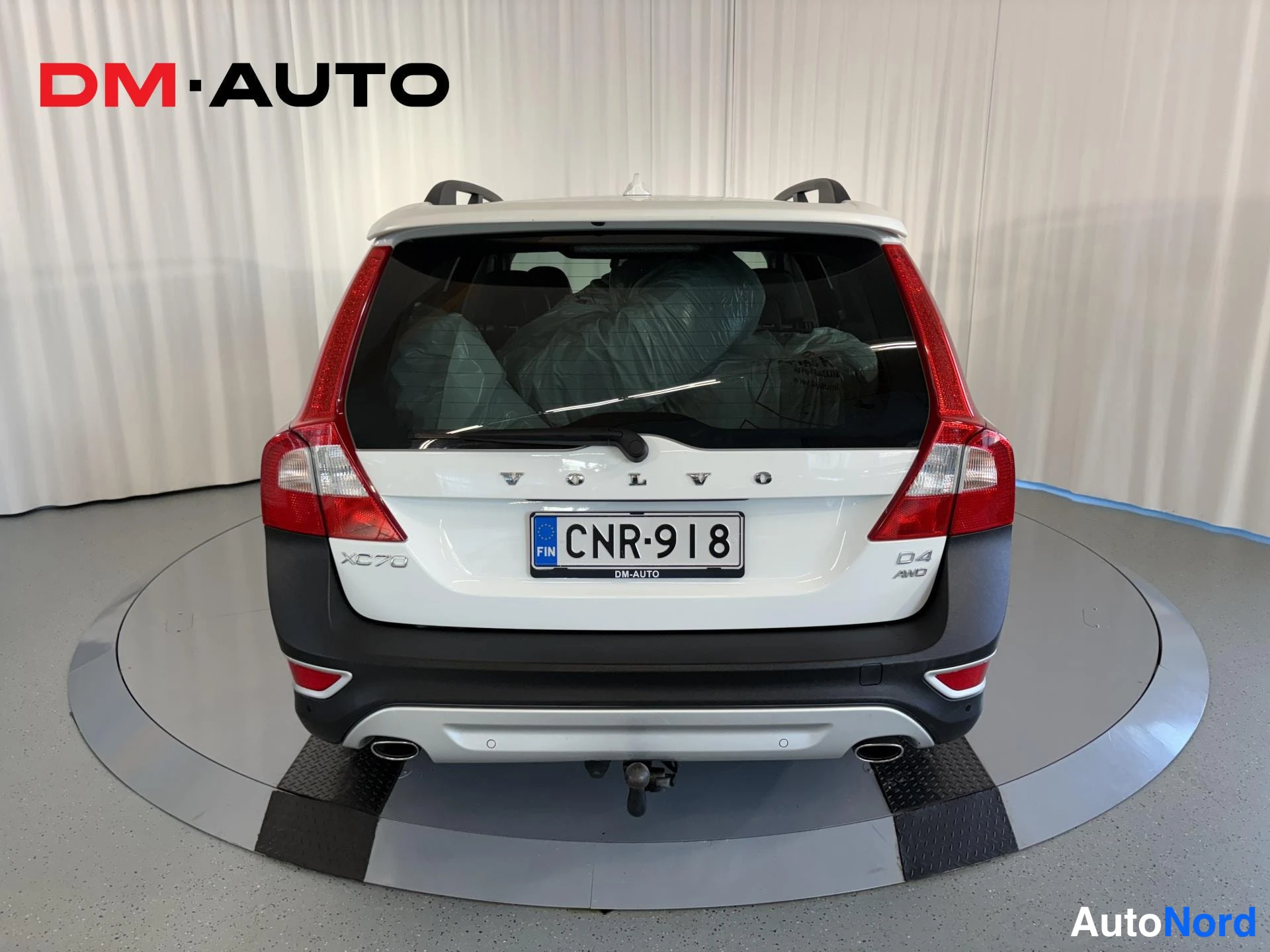 Takaa: Valkoisen farmariauton takaosa suoraan takaa: VOLVO-merkintä, XC70- ja D4 AWD-tunnuks sekä rekisteritunnus.