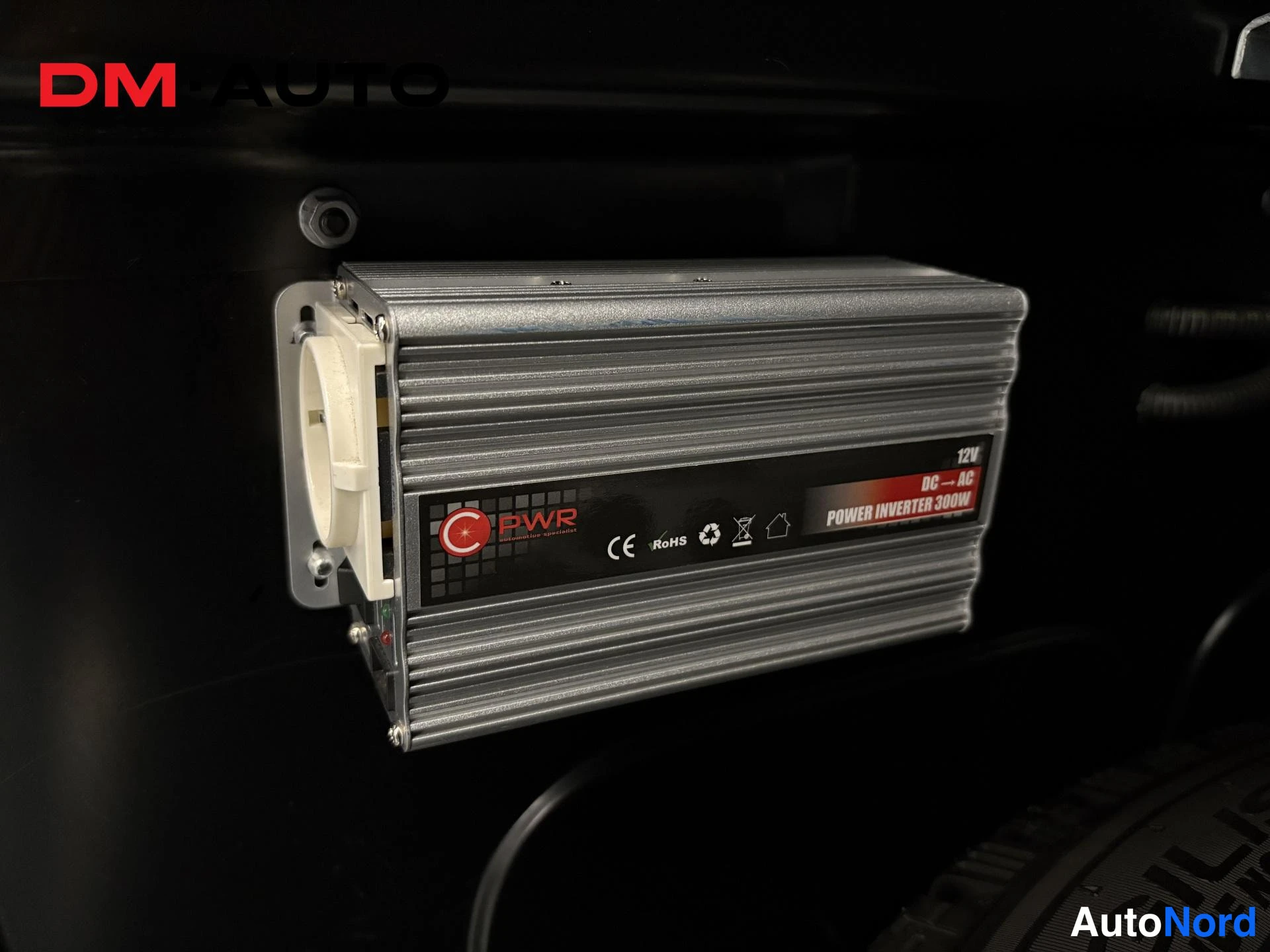 Yksityiskohta: Sisätiloissa asennettu CPWR 12V POWER INVERTER 300W - väristäjä, jossa valkoinen pistorasia.