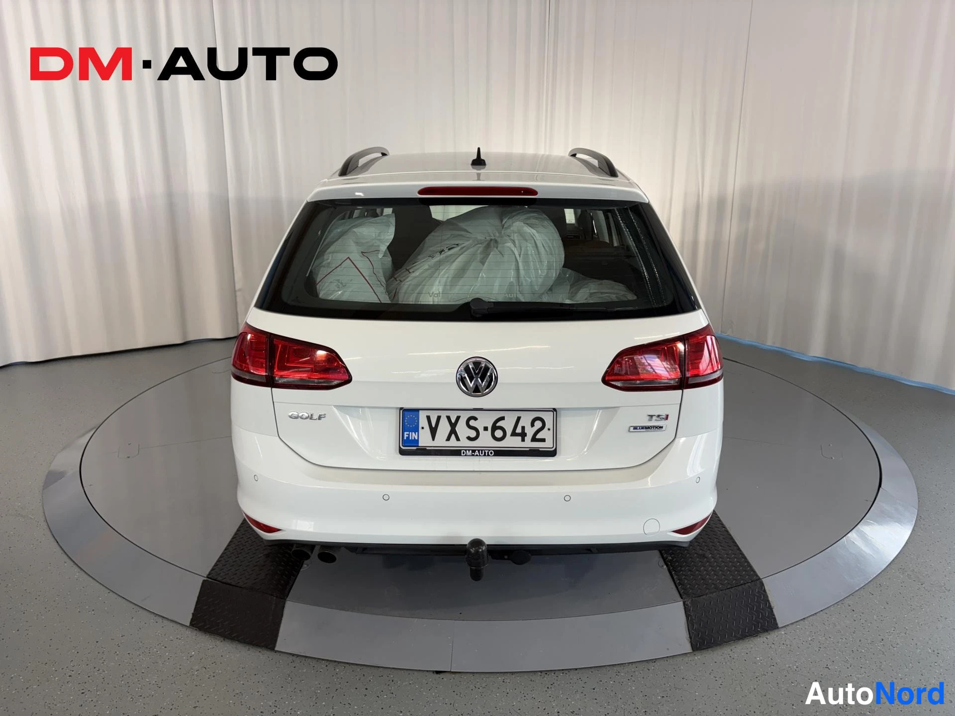 Takaa: Valkoisen farmariauto Volkkari Golf Variantin takanäkö, punaiset takavalot, GOLF-merkintä ja FIN -kilpi suorassa takakuvassa.