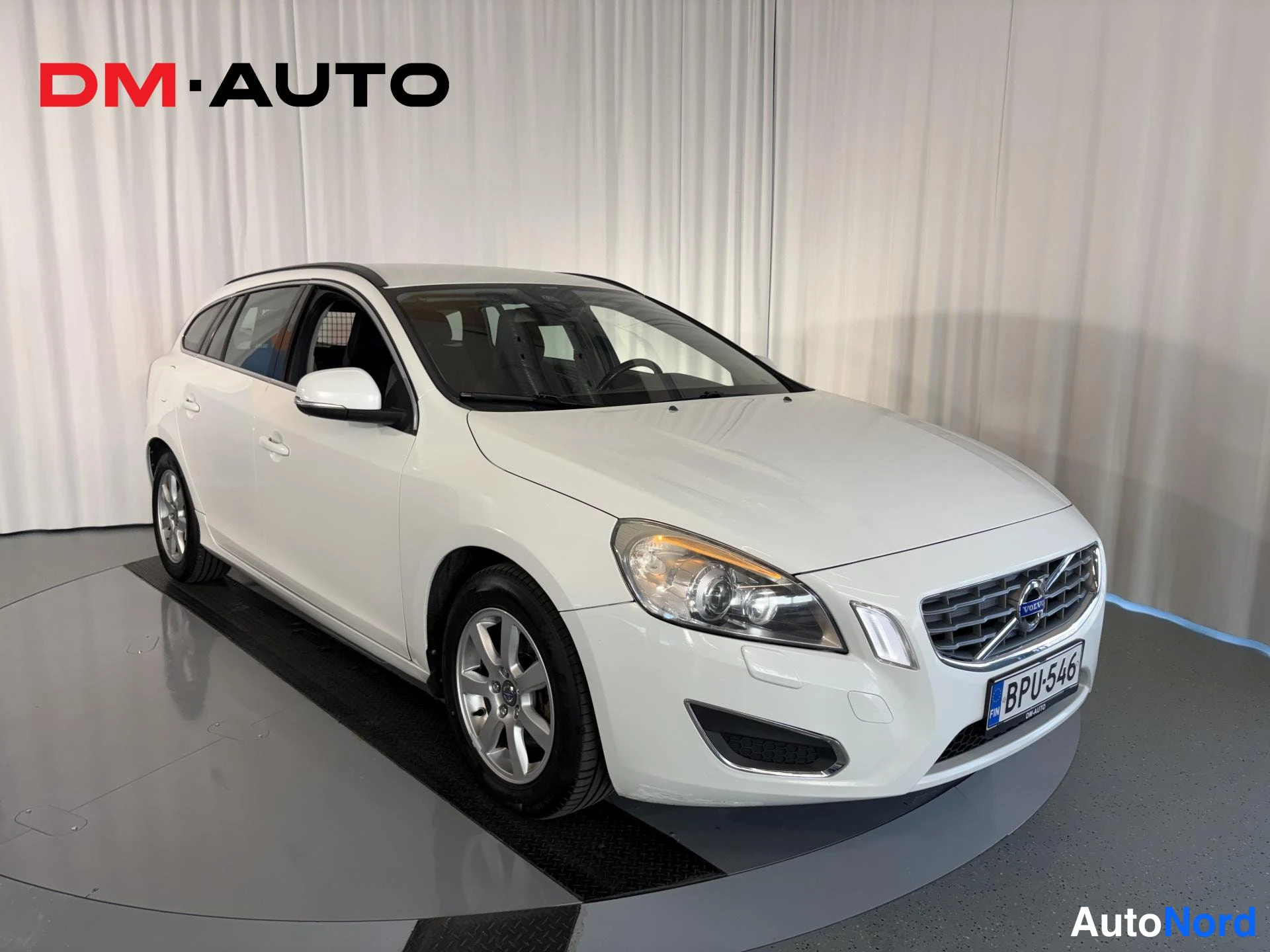 Etuviisto, nokka oikealle: Etukulmasta oikealta valkoinen Volvo V60 -asema-auto, rekisterikilpi