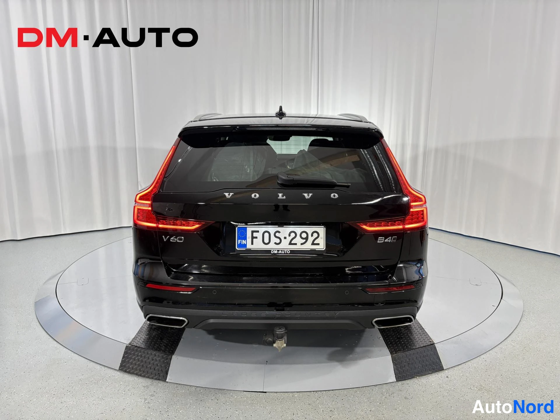 Takaa: Mustan farmariauton suora takaosa; Volvo-kirjaimet, V60- ja B4-merkinnät, punaiset takavalot sekä FIN -rekisterikilpi, vetokoukun tappi puskurin alla.