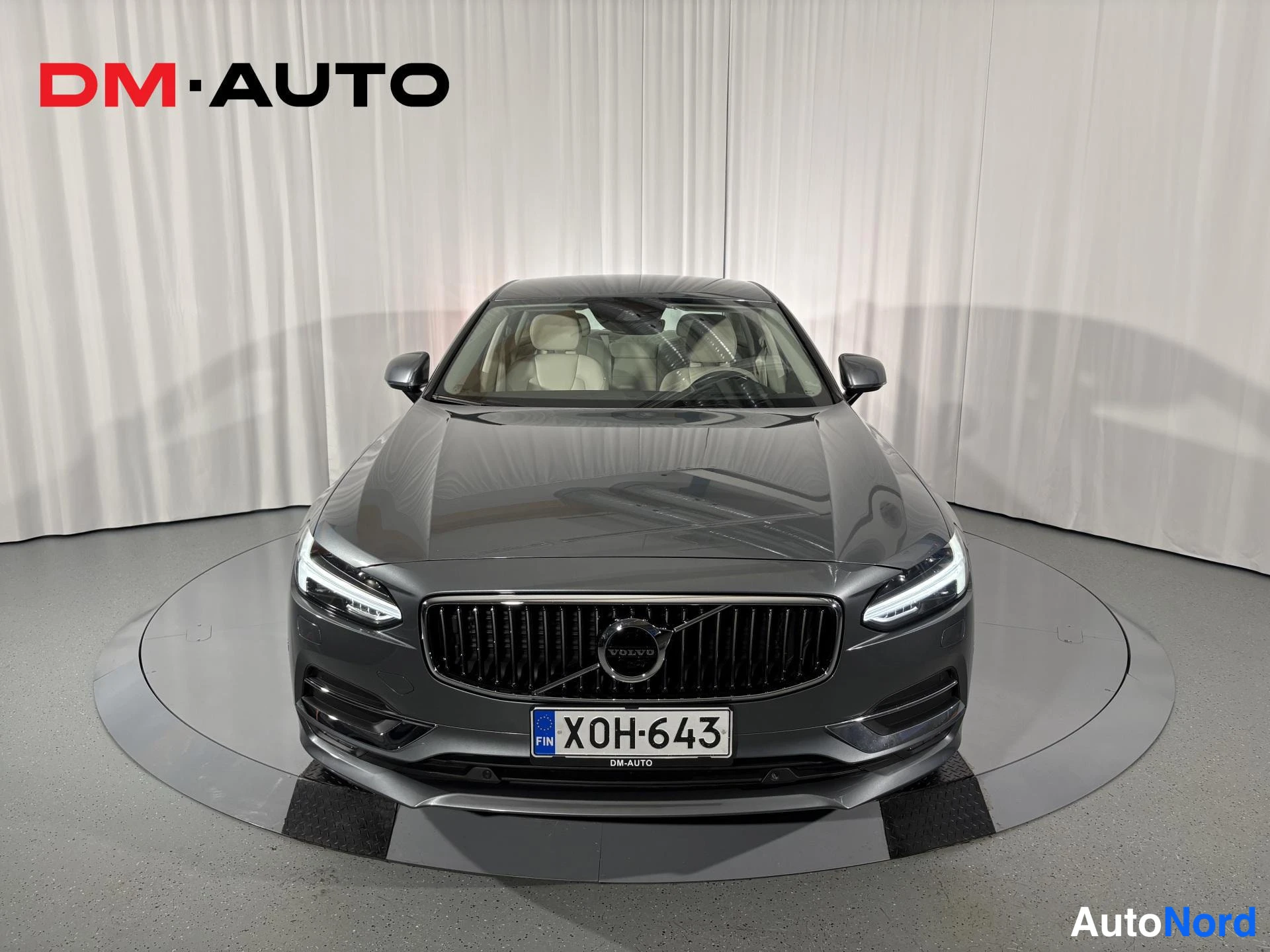 Edestä: Harmaa sedan suoraan edestä,Volvo-grilli ja rekisterikilpi keskitettynä.