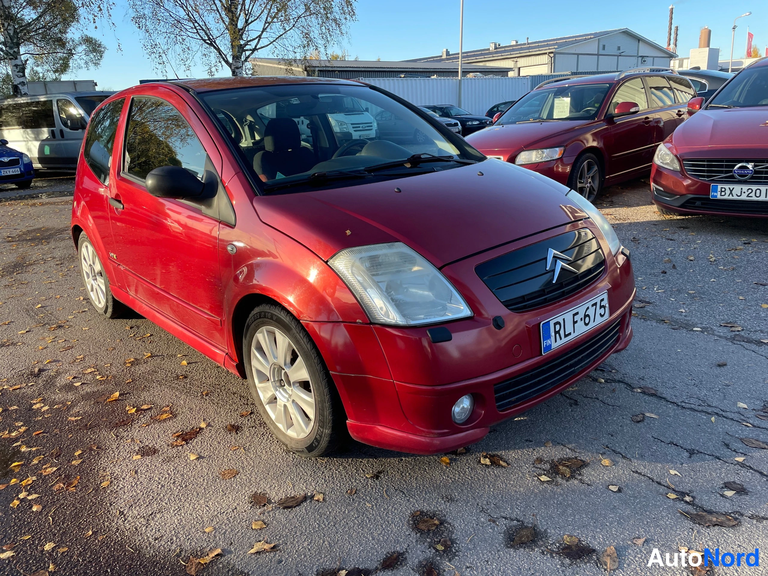 Etuviisto, nokka oikealle: Punainen henkilöauto etuosa kolmivartalokuvassa, rekisterikilpi.