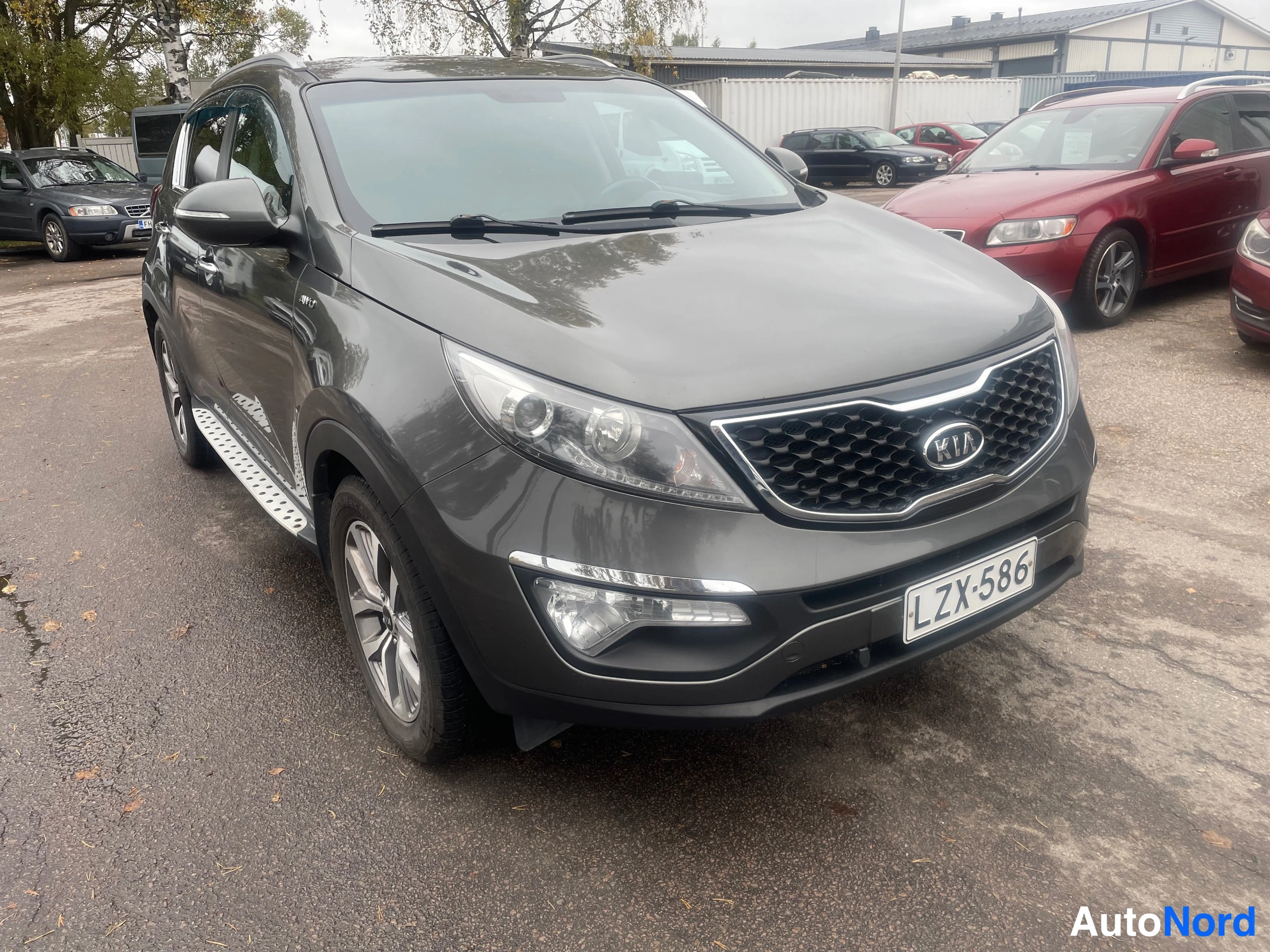 Etuviisto, nokka oikealle: Tummanharmaa Kia SUV kolmella neljäsosasta kuvattuna etuosasta oikealta.