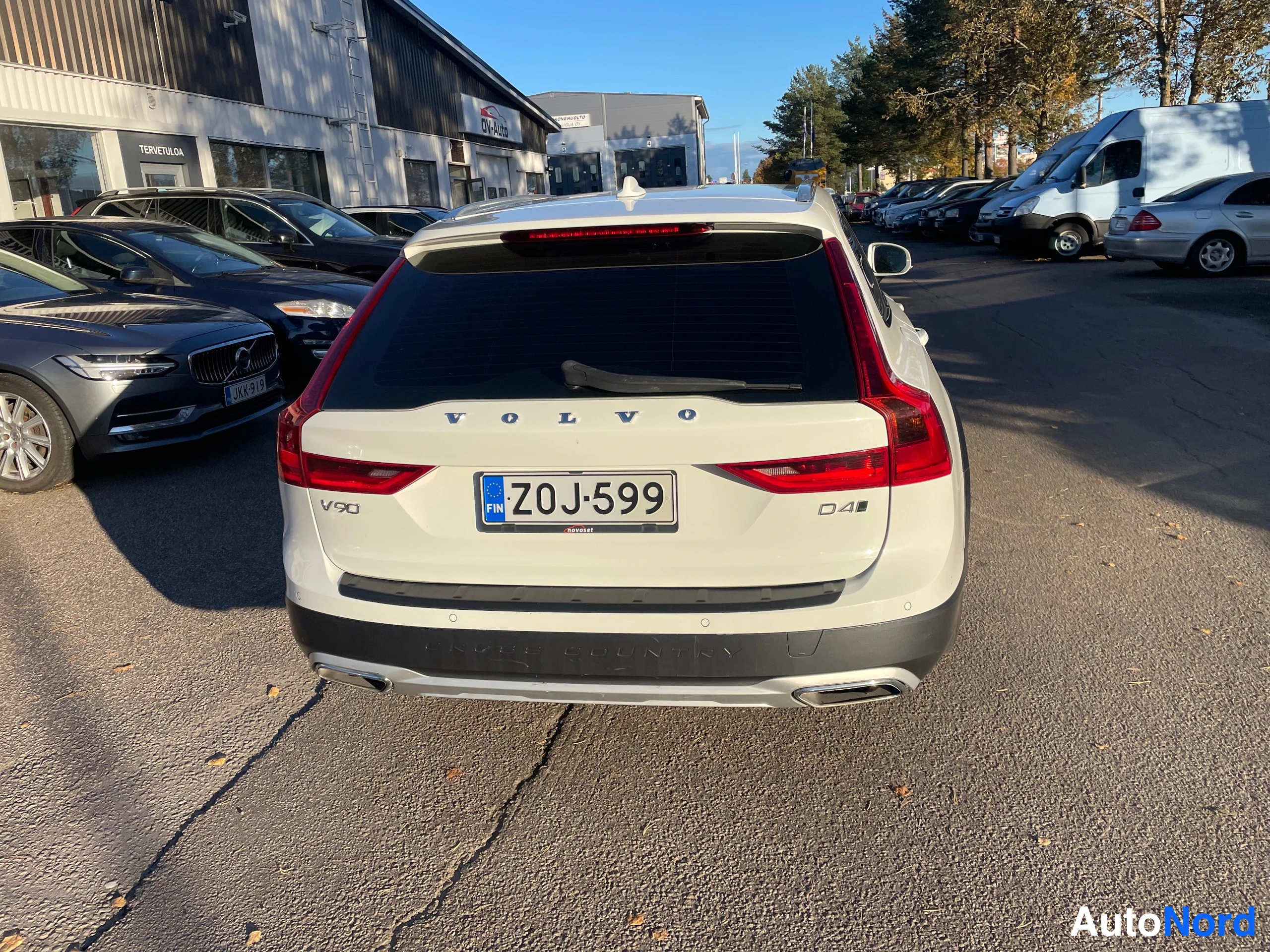 Takaa: Takaapäin valkoinen farmariauto, VOLVO-teksti, V90- ja D4-merkit sekä rekisterikilpi näkyvät.