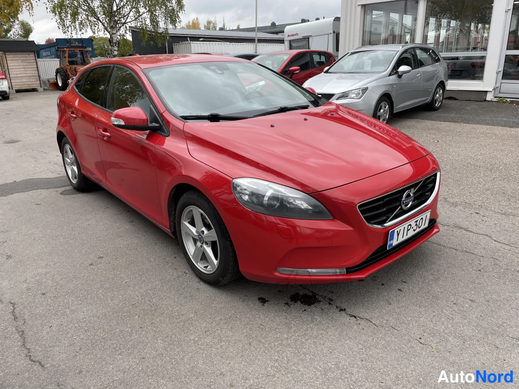 Etuviisto, nokka oikealle: Punaisen Volvo V40:n etukulmanäyttö; etusäleikkö ja etupyörät näkyvät, rekisteritunnus.