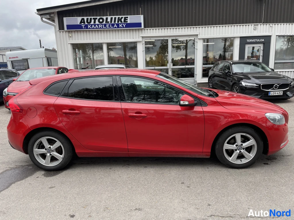 Sivulta: Punaisen Volvo V40:n sivukulmanäyttö katukaupan edessä; molemmat kyljet ja takapyörät näkyvät.