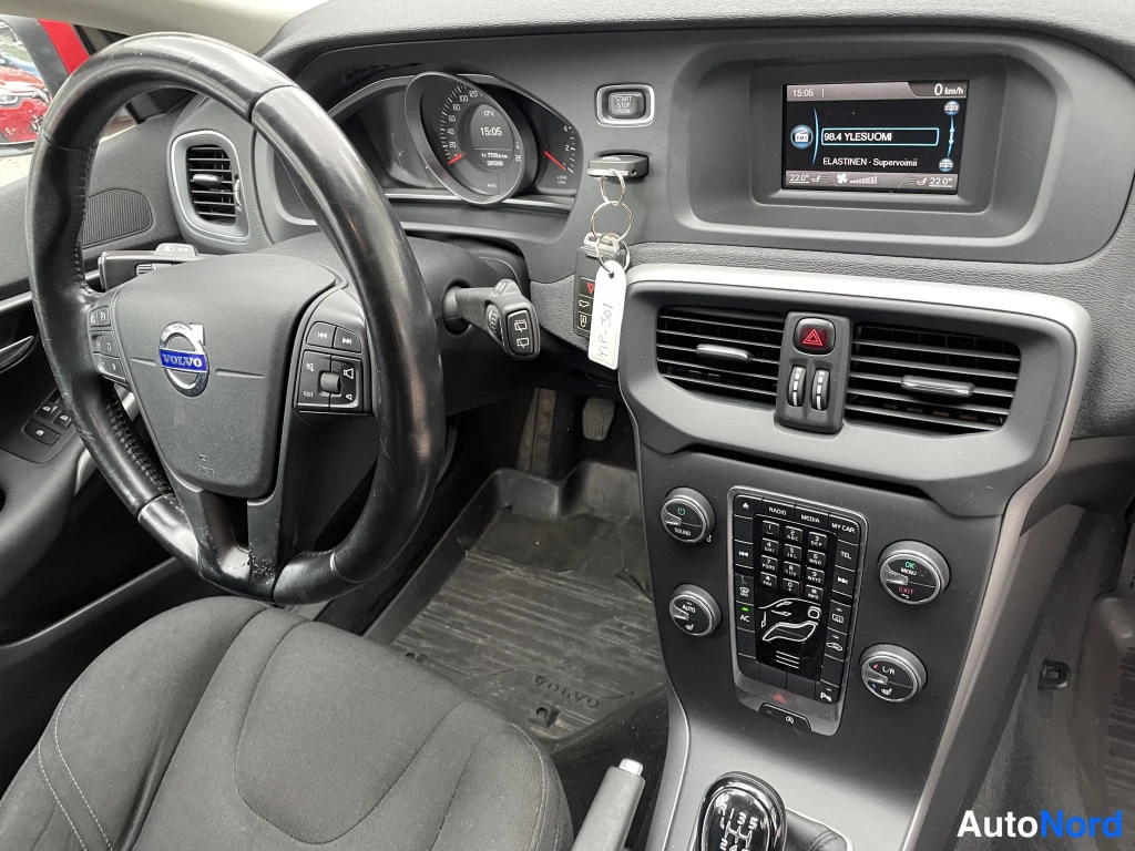 Muu: Volvo-merkkinen ohjauspyörä ja tumma kojelauta radiovalikko näkyvillä keskikonsolissa.