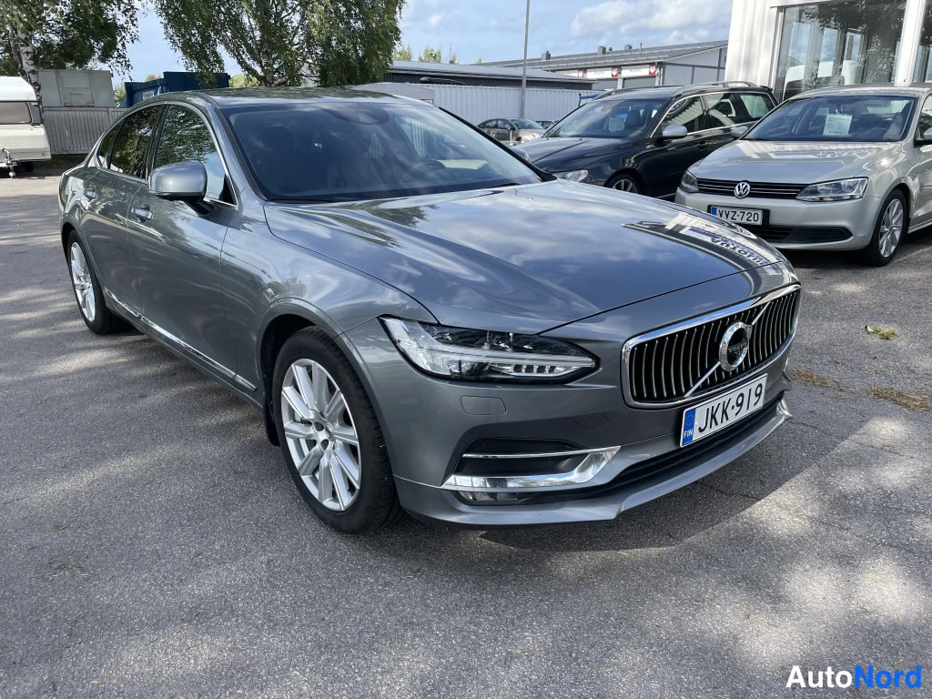 Etuviisto, nokka oikealle: Harmaa Volvo S90 -sedanin keulakulma, keula ja oikea kylki näkyvissä, rekisteritunnus.
