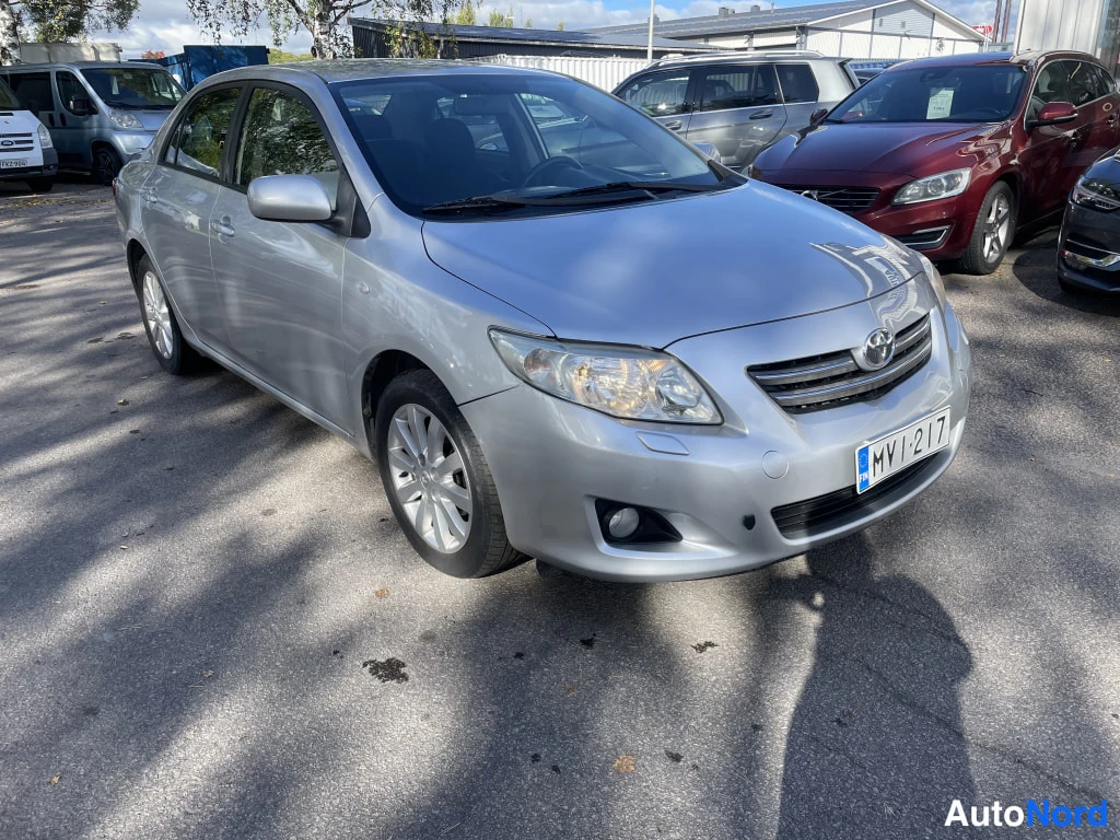 Etuviisto, nokka oikealle: Hopeanharmaa Toyota Corolla -sedan etuokolikuva, rekisteritunnus.