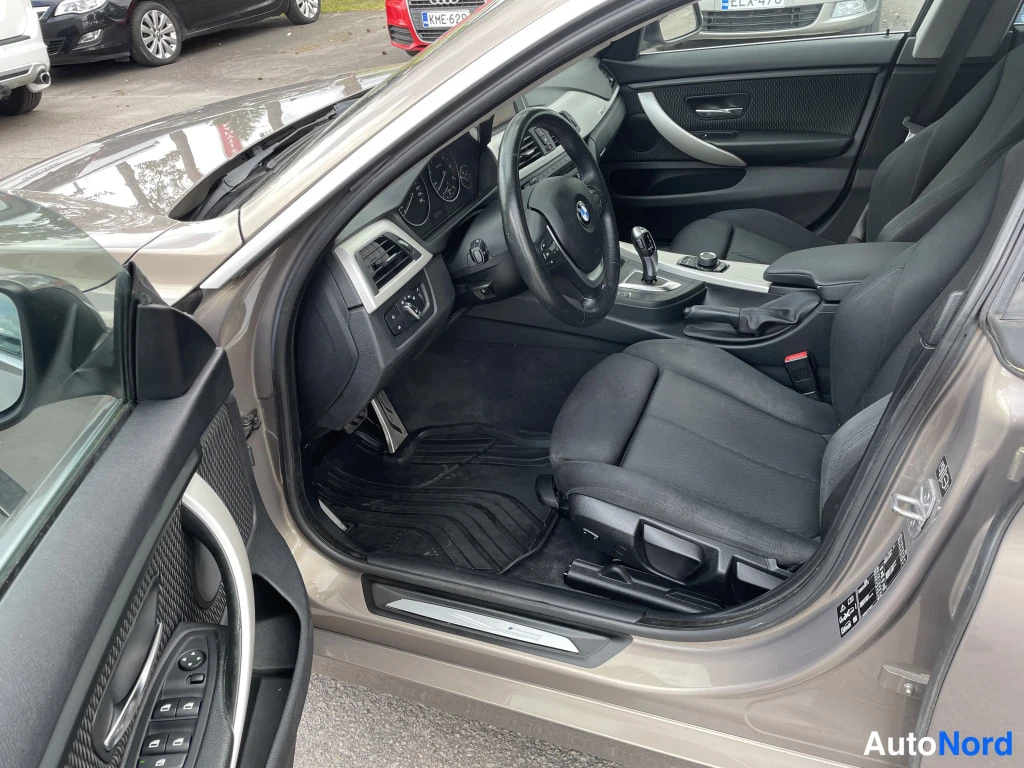 Sivulta: Auton etuistuimille avattu etuovi: tummanharmaa verhoilupinta, halutessa BMW-merkki ratin keskellä.