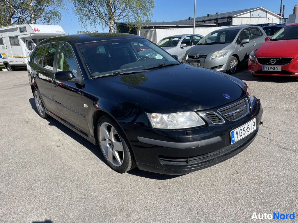 Etuviisto, nokka oikealle: Musta Saab 9-3 SportCombias edestä vasemmalta kolmanneskulmasta, etusäiliö ja rekisterikilpi näkyvissä.