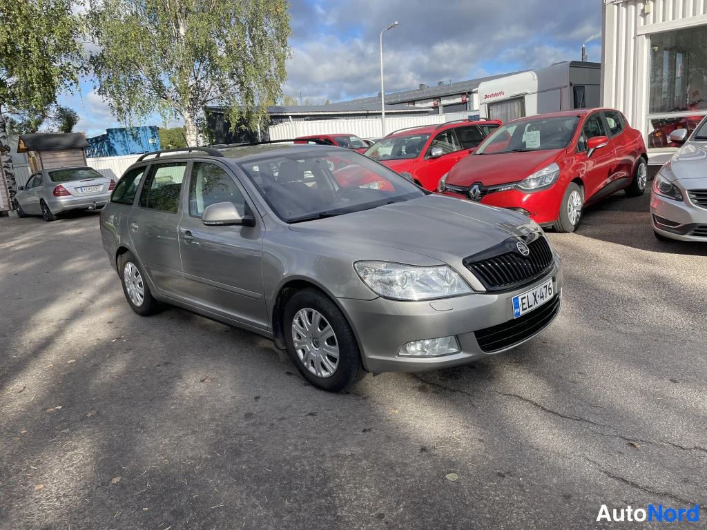 Etuviisto, nokka oikealle: Hopeanharmaa farmariauto kolmannelta sektorilta kuvattuna, keula oikealla, kattokaiteet ja hopeavanteet näkyvissä.