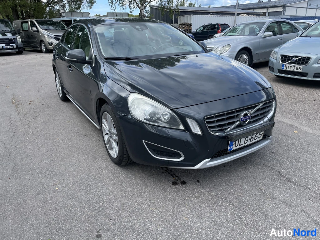 Etuviisto, nokka oikealle: Tummanharmaa Volvo S60 -henkilöauto kuvattu etukulmasta oikealta, konepelti ja etusäleikkö näkyvissä.