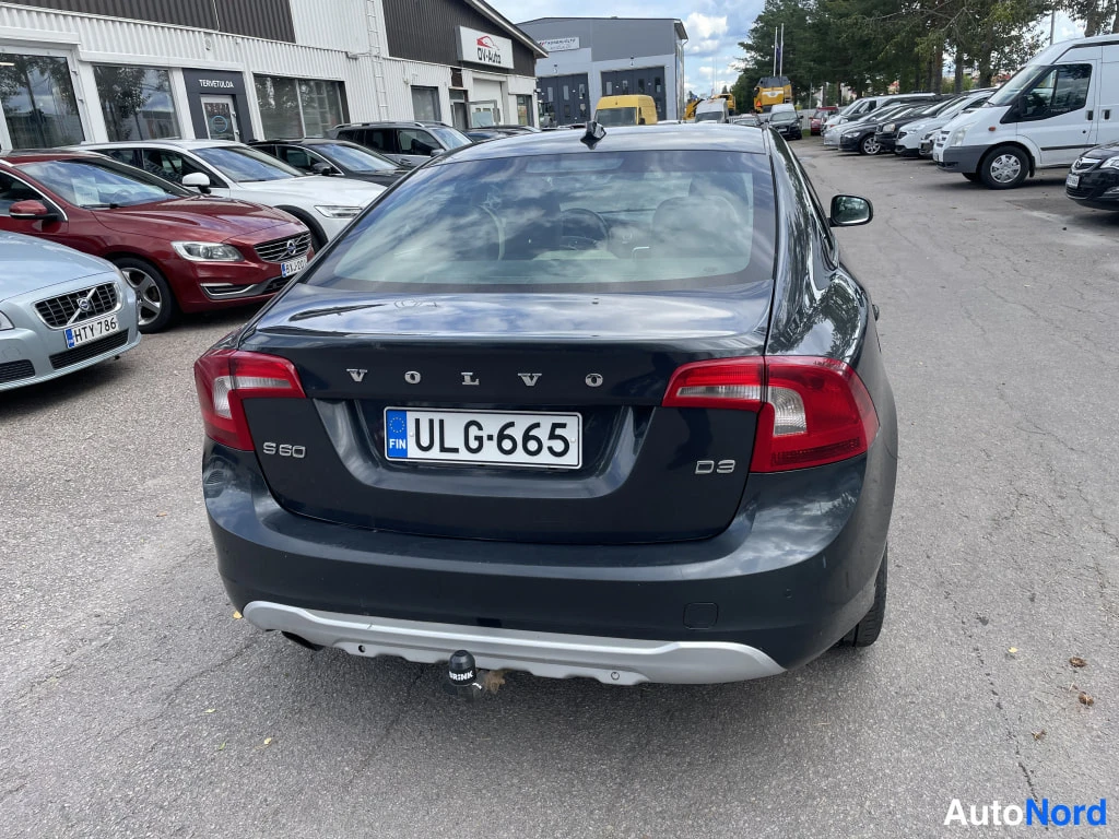 Takaa: Tummanharmaan Volvo S60:n takapää; peräluukussa VOLVO-, S60- ja D3-merkit, rekisterikilpi ja takavetoiskun nuppi.