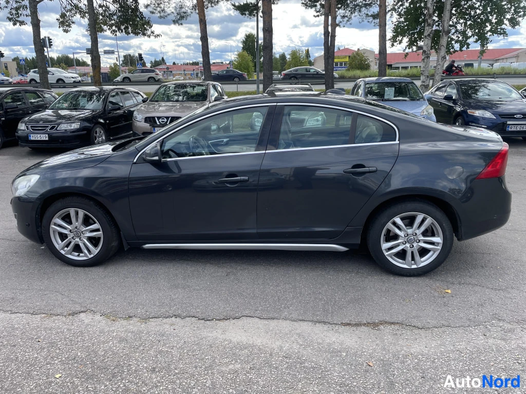 Sivulta: Tummanharmaa Volvo S60 -henkilöauto kuvattu kokonaan vasemmalta sivulta parkkipaikalla.