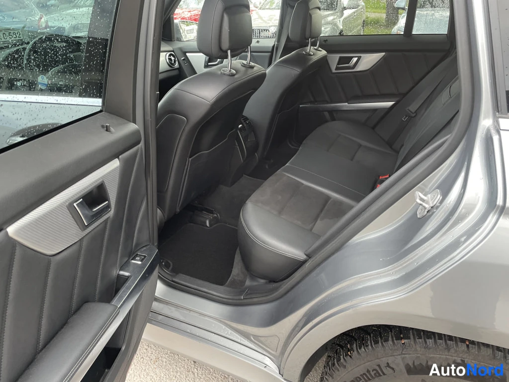 Muu: Mercedes-Benz GLK:n takapenkki vasemmasta takaovesta katsottuna: mustat penkit, tummat matot ja hopeaharmaa kori.