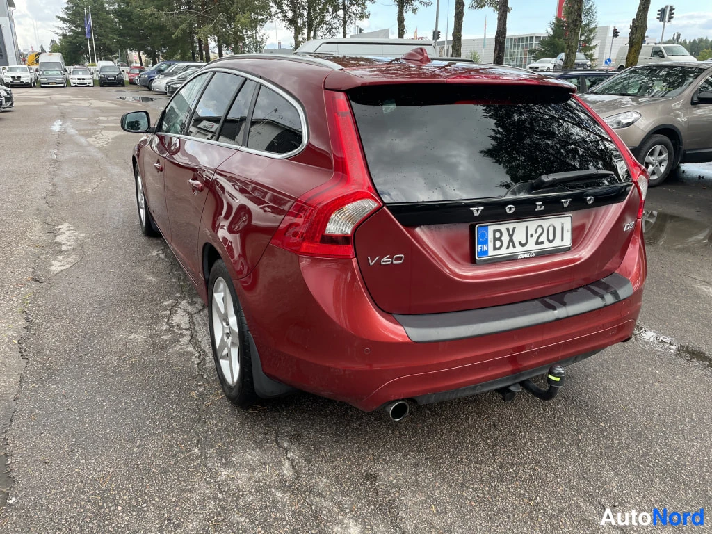 Takaviisto: Punaisen farmariauton takaosa kolmanneltpä takaa vasemmalle kuvattuna märällä parkkipaikalla, rekisterikilpi.