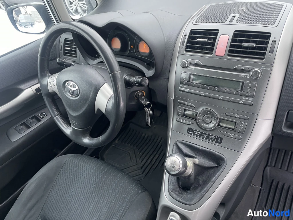 Muu: Kuljettajan paikka: Toyota-ohjauspyörä, manuaalivaihdin ja kojelaudan hallintayksikkö napoineen ja näytöineen.