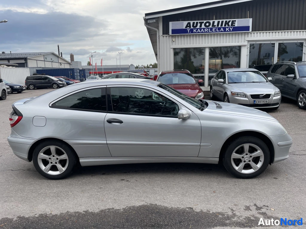 Sivulta: Hopeanvärinen Mercedes-Benz C-sarjan coupe sivulta kuvattuna autoliikkeen edessä.