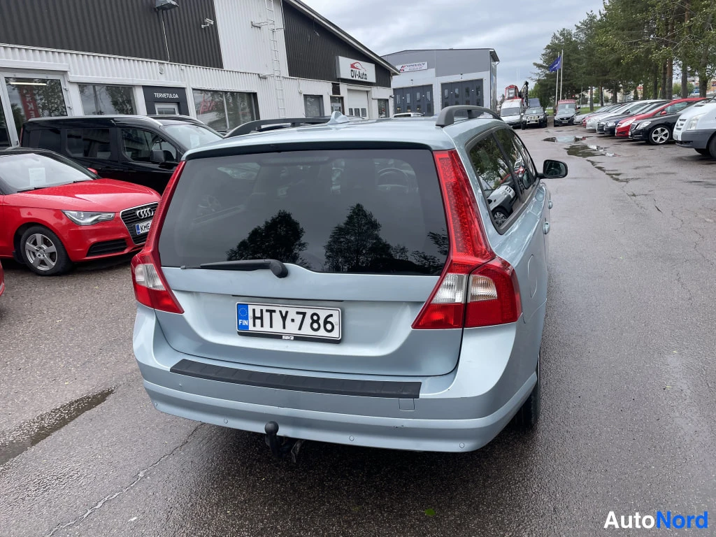Takaa: Vaaleansininen farmariauto takaa kuvattuna, rekisterikilpi ja takavalo näkyvissä.