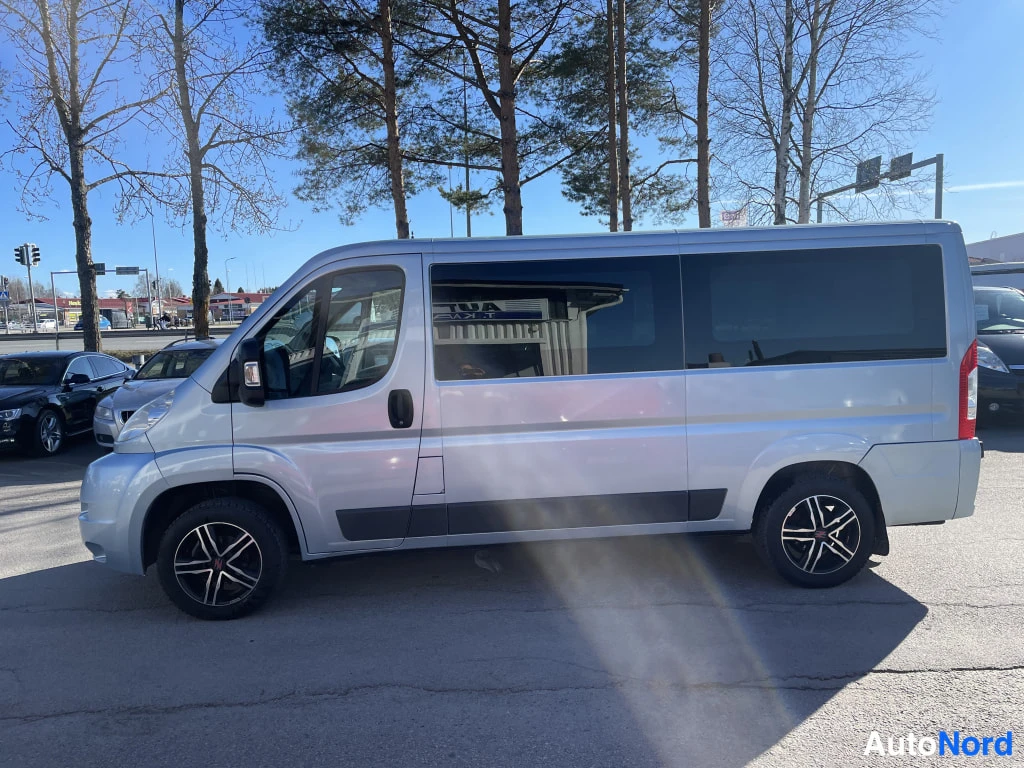 Etuviisto, nokka vasemmalle: Peugeot Boxer -pakettiauto vasemmalta etuviistöstä, vaaleansininen koripinta ja pitkä kylki tummine ikkunoineen.