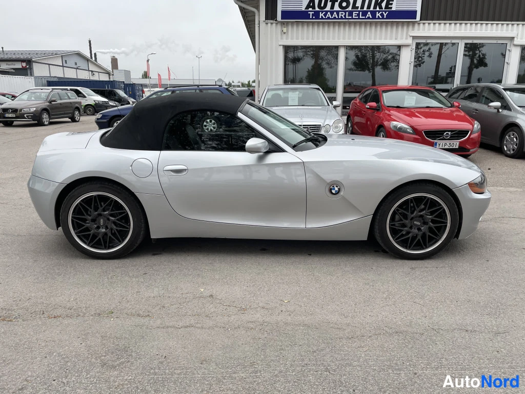 Etuviisto, nokka oikealle: Hopeanvärinen BMW Z4-avomalli sivusta oikealta kuvattuna, musta pehmeä katto ja mustat vanteet.