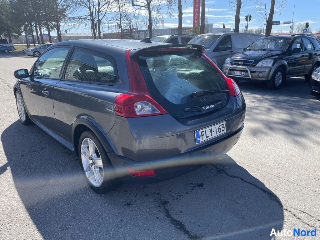 Takaviisto: Tummanharmaan hatchbackin takaosa ja vasen kylki kolmesta neljäsosasta taakse kuvattuna, rekisterikilpi.