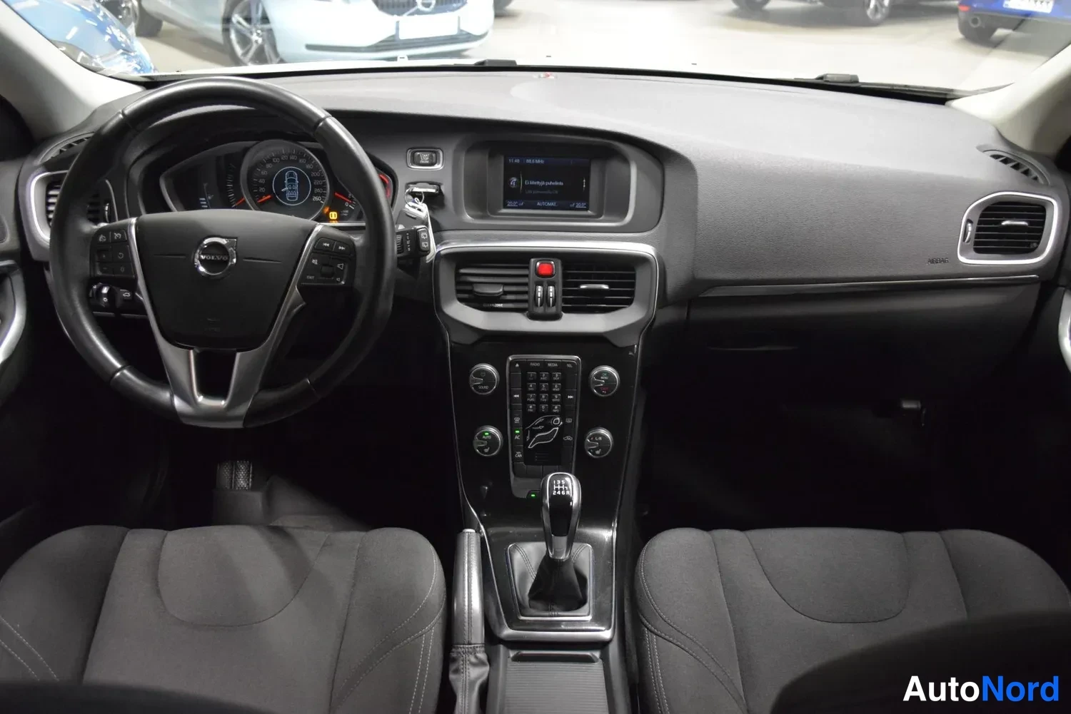 Muu: Volvo V40:n sisätilat: ohjauspyörä, kojelauta, keskikonsoli ja manuaali vaihteenvalitsin, tummat kangasistuimet.