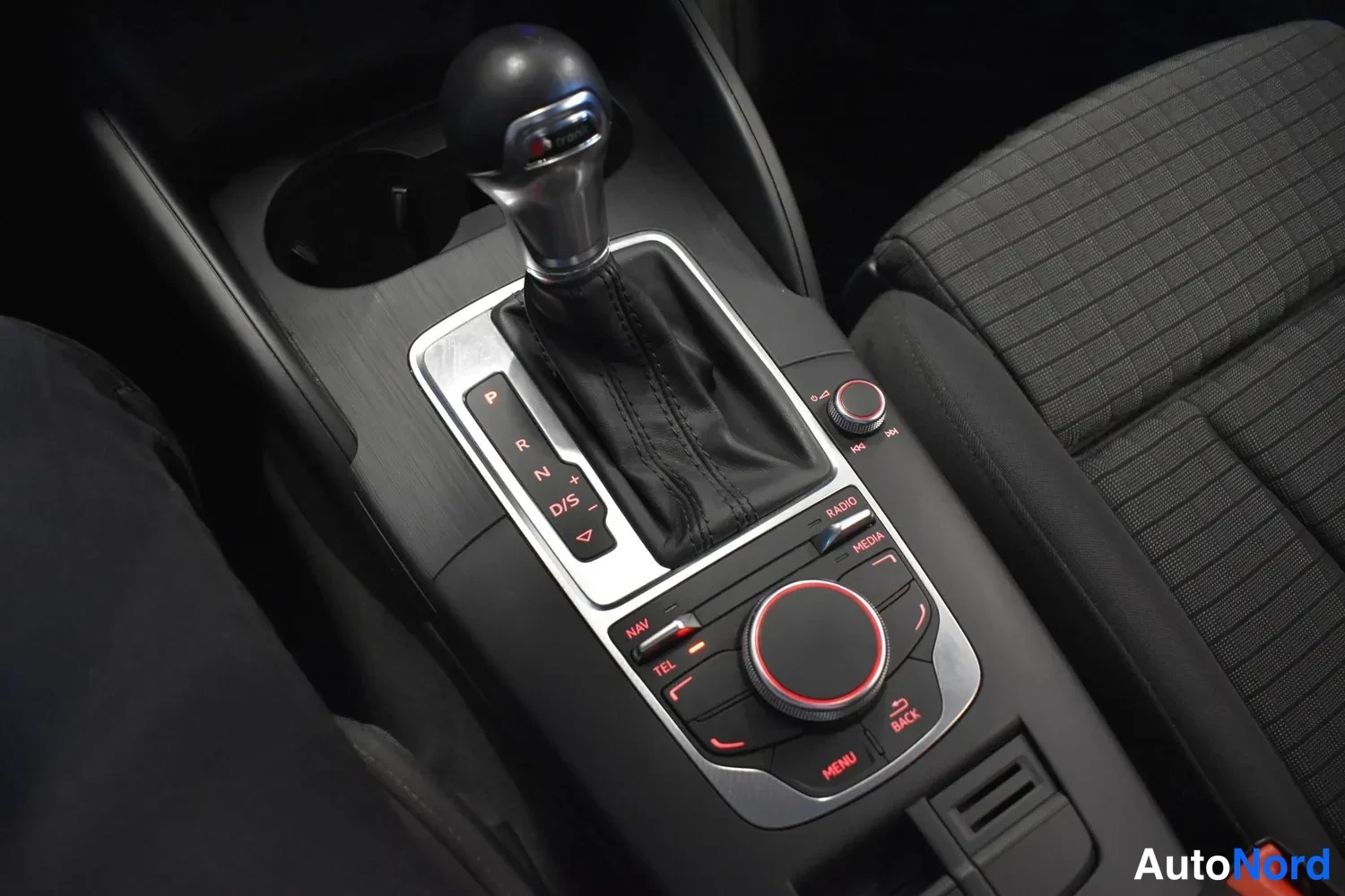 Yksityiskohta: Automaattivaihteen P R N D/S -valitsin ja keskikonsolin MMI-nappirivi RADIO, MEDIA, NAV, TEL, MENU, BACK.