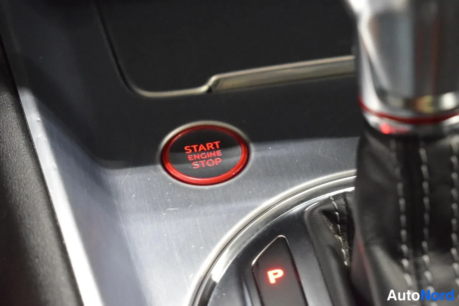 Muu: Audi S tronic -vaihteenvalitsin ja punainen START ENGINE STOP -käynnistyspainike keskikonsolissa, vaihteen P valaistuna.
