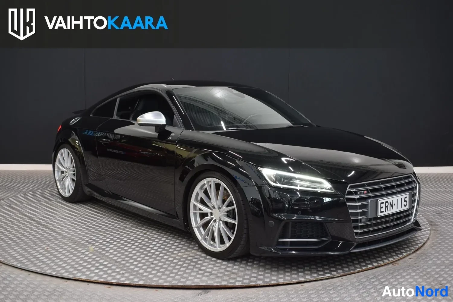 Etuviisto, nokka oikealle: Mustan Audi TT Coupén etuosa kulmasta oikealta, LED-ajovalot ja grille näkyvät.