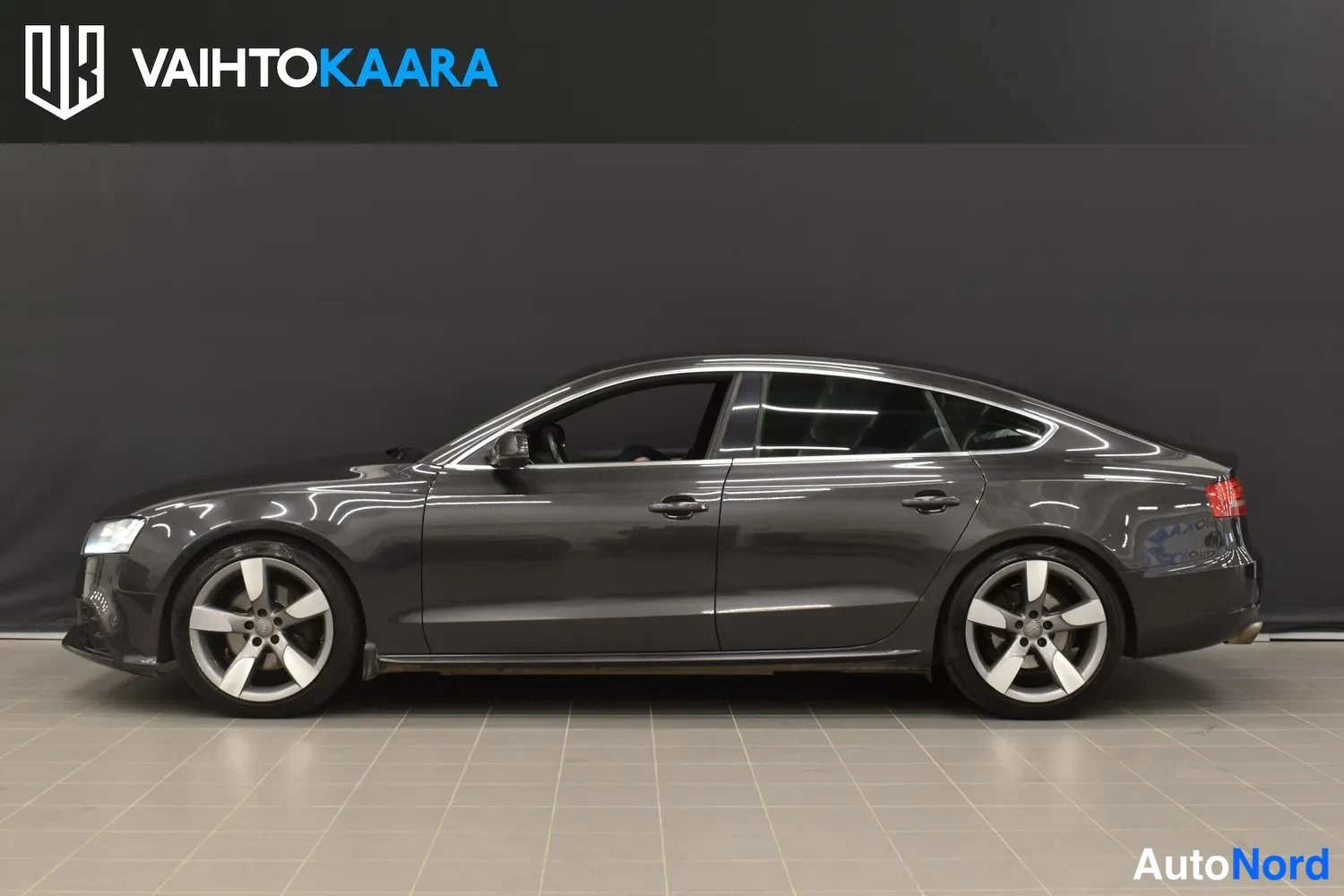 Sivulta: Audi A5 Sportback sivukuva vasemmalta, tummanharmaa kori ja hopeat vanteet.